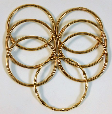 Six plain 9ct gold bangles twinned with one yellow metal bangle, tests as 9ct gold, SOLD £620